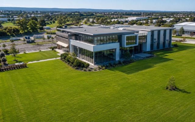 Aerial view of a large lush green lawn surrounding a modern commercial building in South East Queensland established by hydroseeding